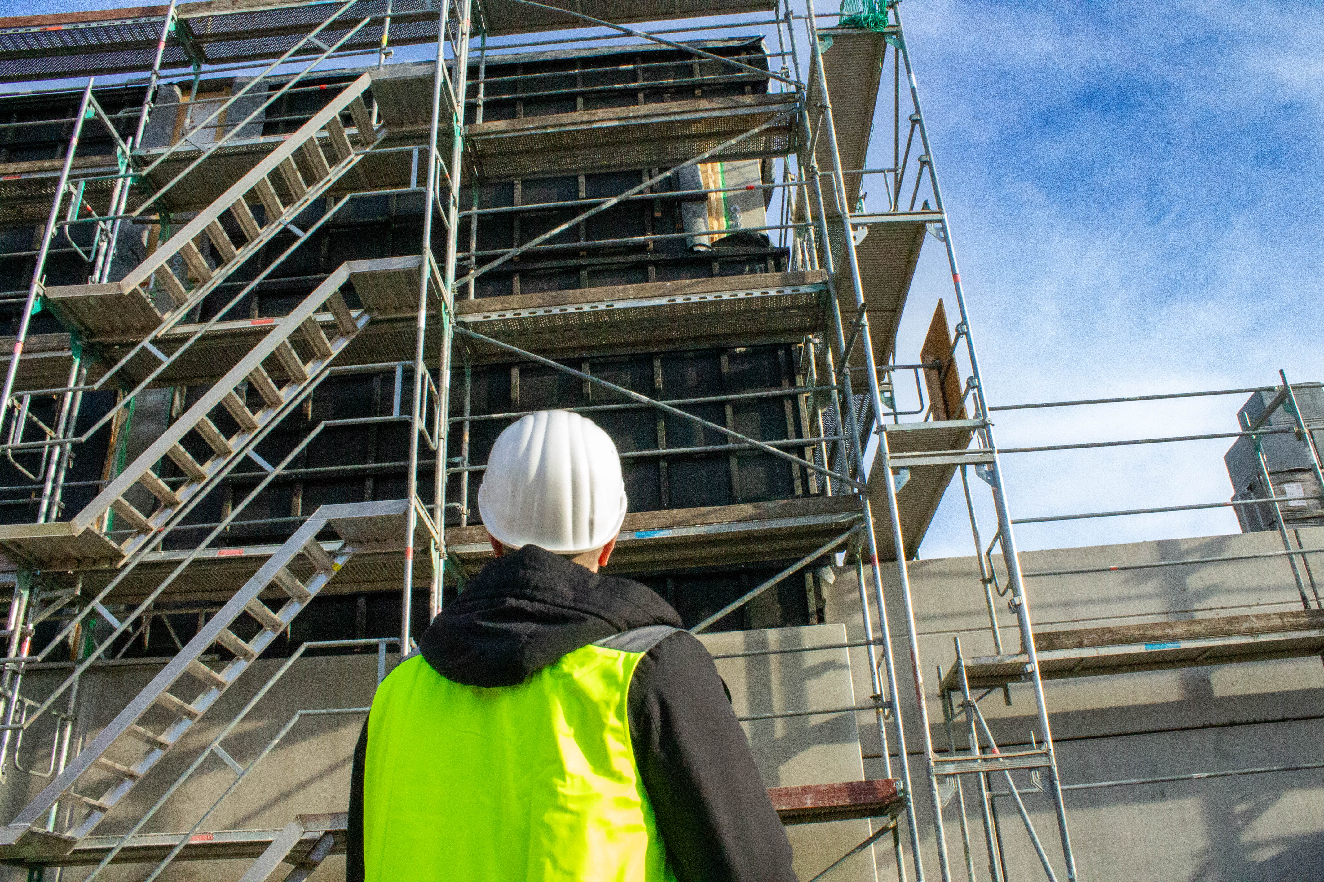 Bild von Sedin Delić, welcher nach oben auf ein Baugerüst schaut.