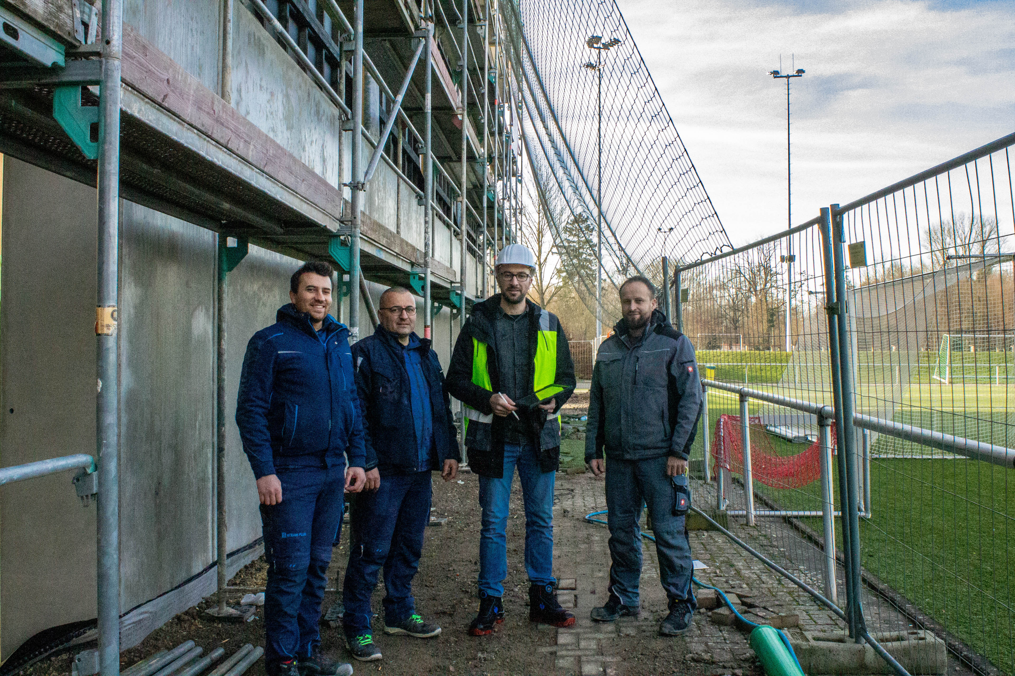 Bild einer Baugruppe von D-Neu, welche gemeinsam vor einem Bauprojekt stehen.